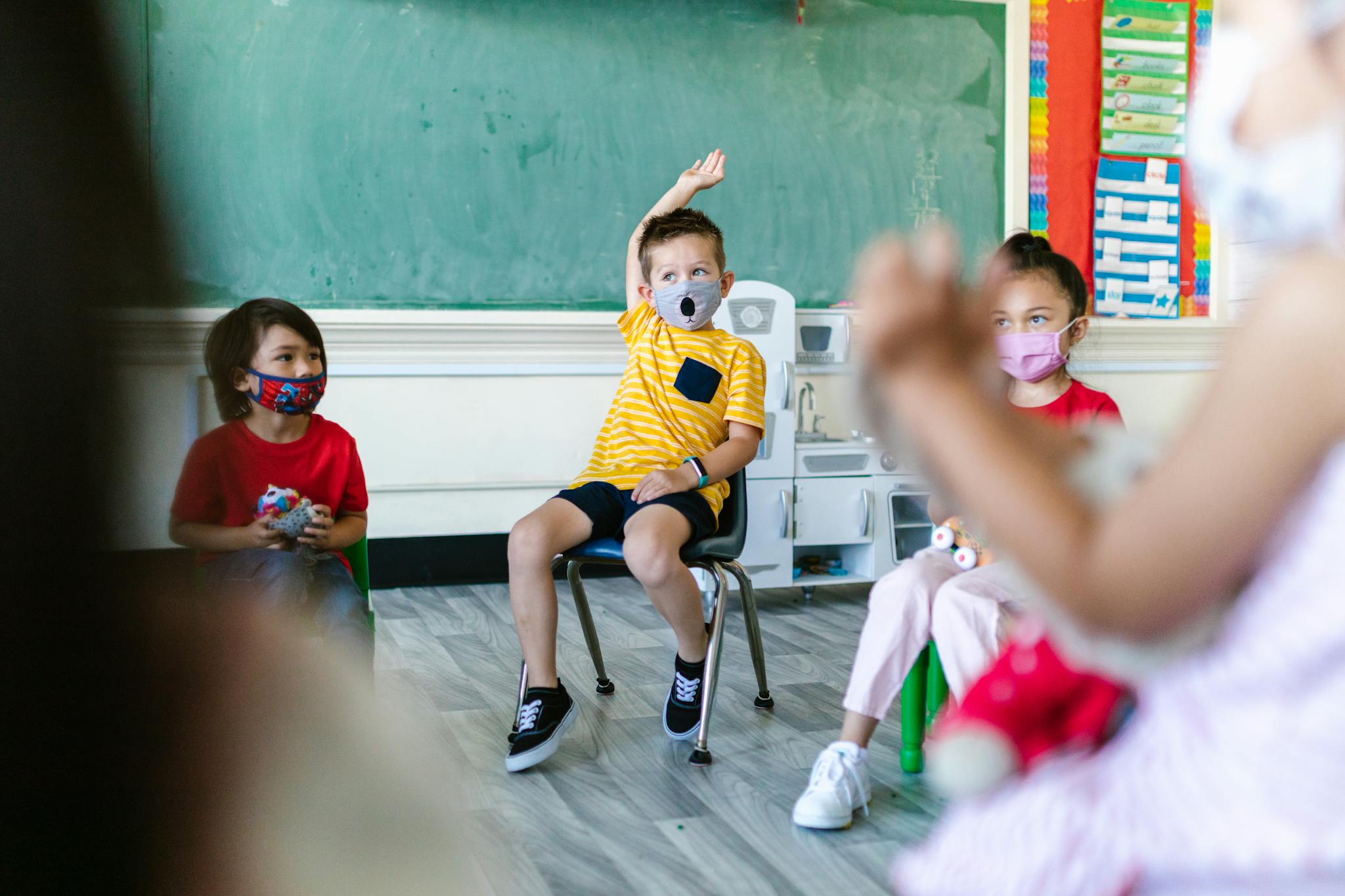 Preschool children wearing face masks participate in classroom activities, adapting to new normal routines.